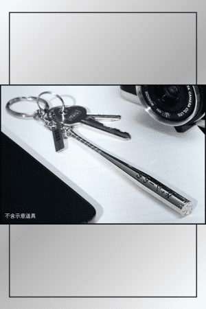 Dandadan Seiko Ayase baseball bat keychain attached to a keyring with house keys, placed on a desk beside a laptop and camera